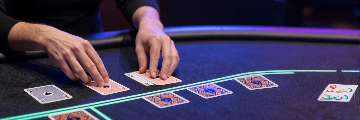 Live-Dealer-H&auml;nde geben Karten an einem neon-beleuchteten Blackjack-Tisch im Casoola Live Casino